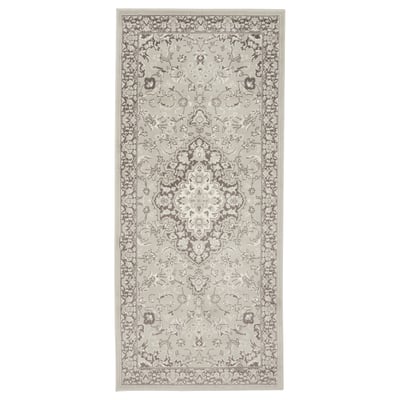 A grey VEDBÄK rug with a floral pattern. It is rectangular and made of polypropylene.