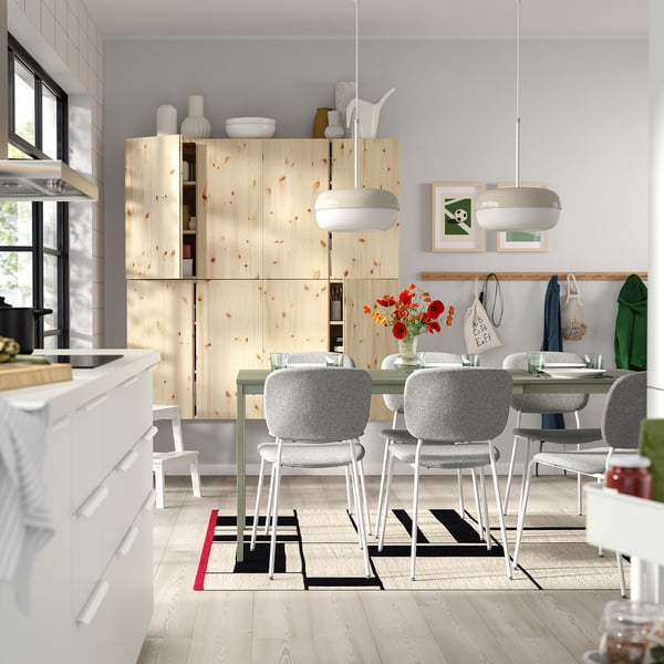 Modern kitchen with pine cabinets, white chairs, and a vibrant rug.