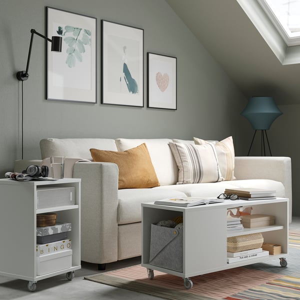 Modern living room with grey sofa, striped pillows, storage units, and minimalist artwork.