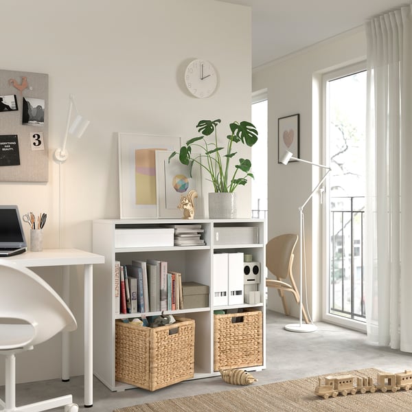 Modern white home office with table, chair, shelves, and plants.