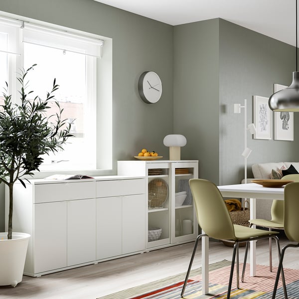 Modern dining room with VIHALS white storage, glass doors, and pale green chairs beside a window.