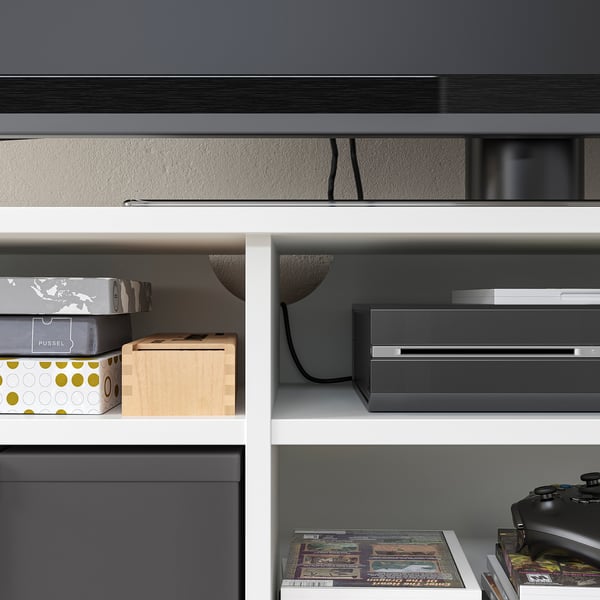 Modern white tv stand with 2 drawers, 3 shelves, and cable management in back, holding various storage boxes and electronics.