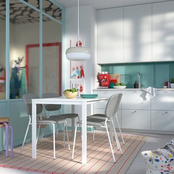 Clean dining area with VIHALS white table, four grey chairs, and sleek kitchen cabinets. Modern design with simple decor.