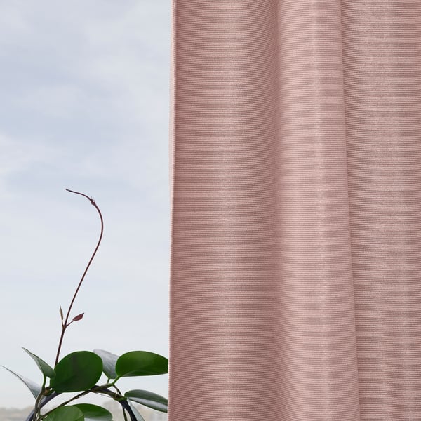 Sheer pink curtains with light-blocking fabric hang by a window, framing green leaves of a plant.
