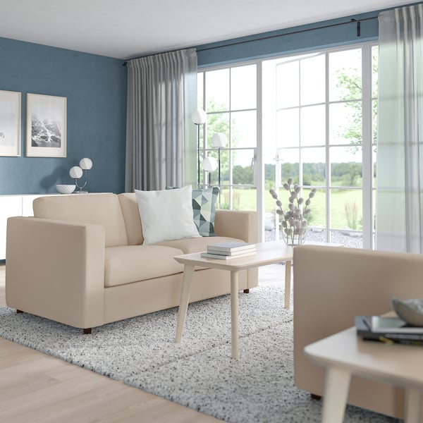 Contemporary living room with beige sofa, white coffee table, blue walls, and natural light.
