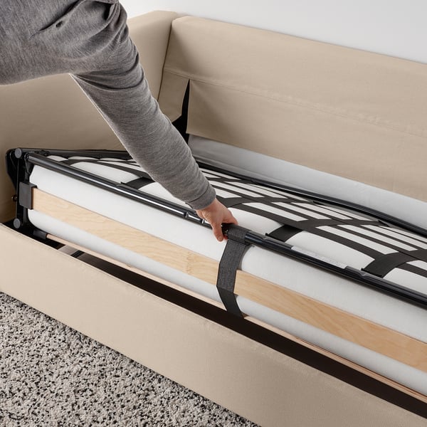 Person adjusting a VIMLE sofa-beds frame, preparing it for use.