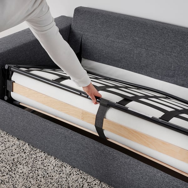 Person pulling out mattress from sofa-bed frame, demonstrating its easy conversion.