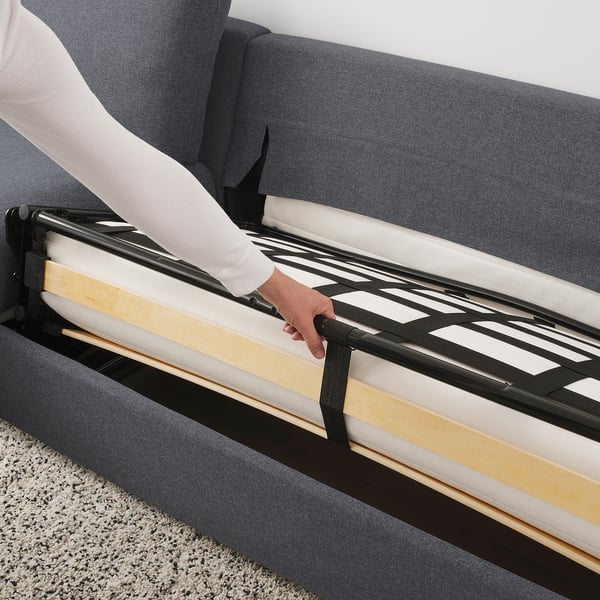 Person pulls out sofa-bed mechanism on grey VIMLE sofa.