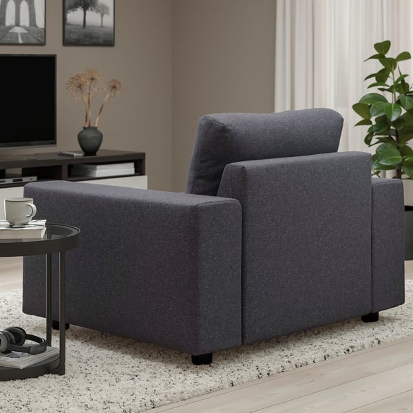 Grey fabric sofa with wide armrests in modern living space.