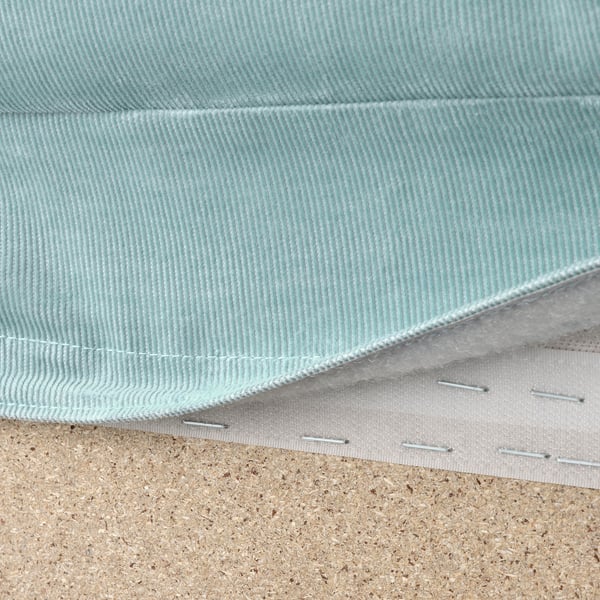 Close-up of washable, light blue VIMLE sofa fabric with white stitching, laid on cork surface.