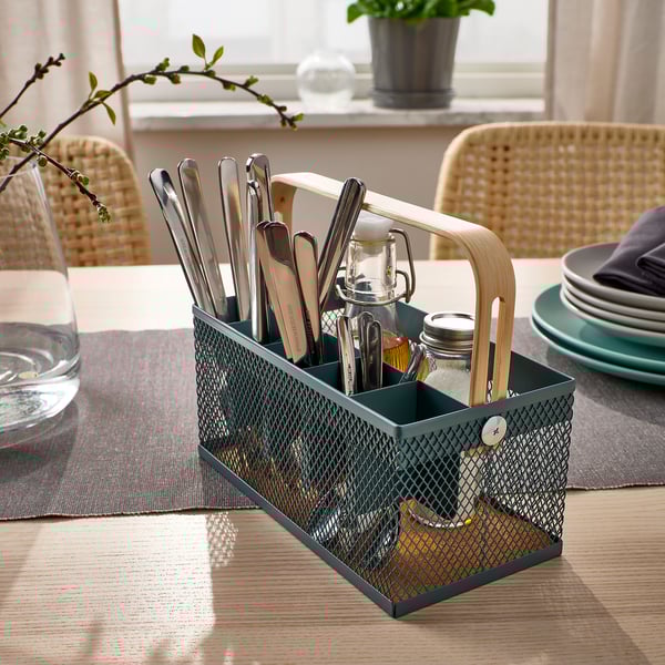 Green metal table caddy with wooden handle stores cutlery, salt, and pepper. Keeps table neat and organised.