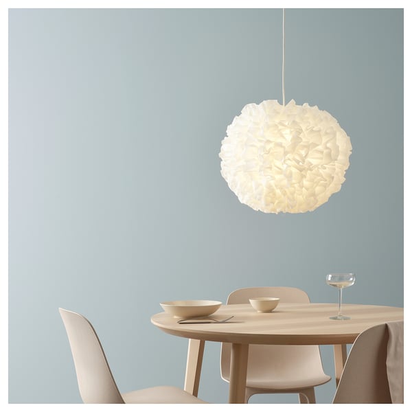 White modern dining room with round table, four beige chairs, and a large white pendant light with a cloud-like shade hanging from the ceiling.