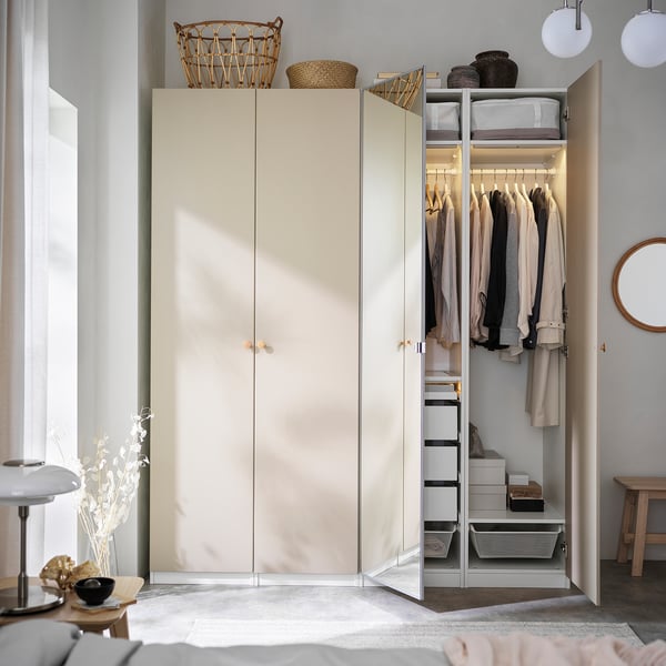 Modern wardrobe with VINNÄSET knobs in beech. Cream-colored, tall, sleek design, fits neatly in room. Holds clothes, baskets, reflected in mirror.