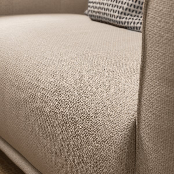 A close-up of the VISKAFORS armchair, featuring its beige fabric, soft rounded shape, and inviting design.