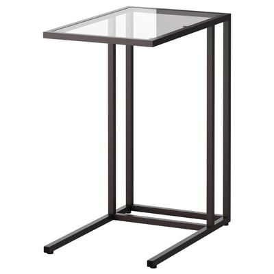 A black VITTSJÖ laptop stand. It a rectangular glass top supported by a metal frame with clean lines and a modern design.