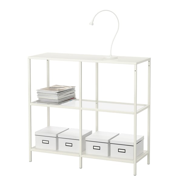 White VITTSJÖ shelving unit with glass and metal. Holds books and storage boxes, includes adjustable feet for uneven floors.