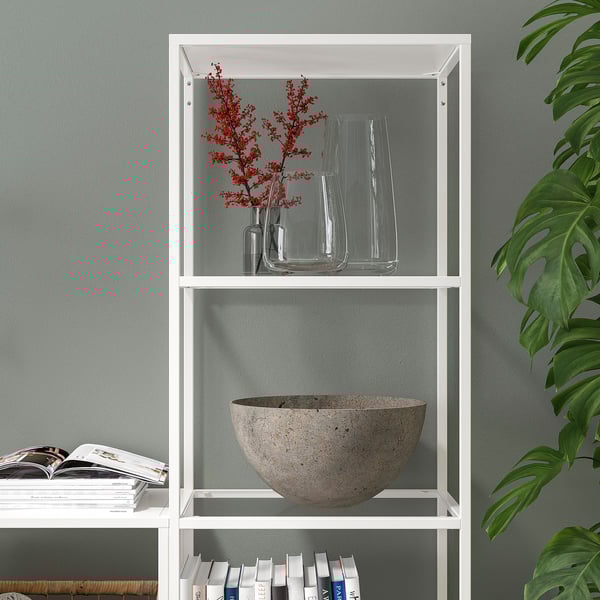 White bookcase with shelves, displaying decorative vases, berries, a large bowl, and books.