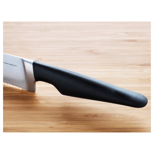 A knife on a wooden cutting board; sharp blade, black handle; high-quality material.