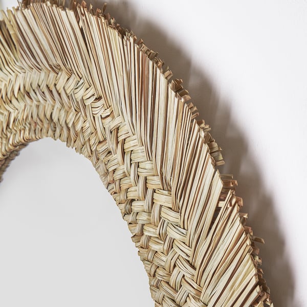 Handwoven natural sedge frame mirror. Intricate, artisanal design with light, earthy tones.