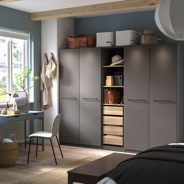 Modern bedroom with grey wardrobe, white chair, wooden floor, and a black lamp.