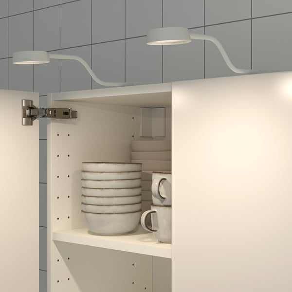 Cabinet light with flexible arm, bending to illuminate stacked bowls.