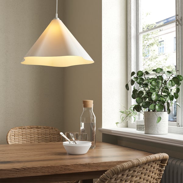 Cozy dining nook with ZEBRASÄV lamp, wooden table, and greenery.
