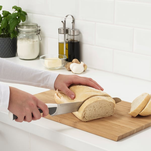 Inimene viilutab köögis lõikelaual noaga leiba.