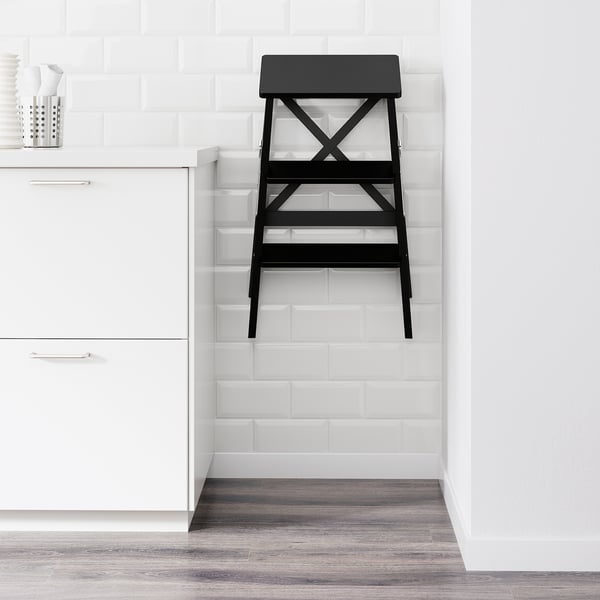 Köögis must trepp vastu valget plaaditud seina, kokkuvolditud kompaktseks hoiustamiseks.