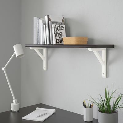 Kaasaegne minimalistlik kodukontori seadistus: must riiul, valge kirjutuslaud, lamp, märkmik, pastakad, taim.