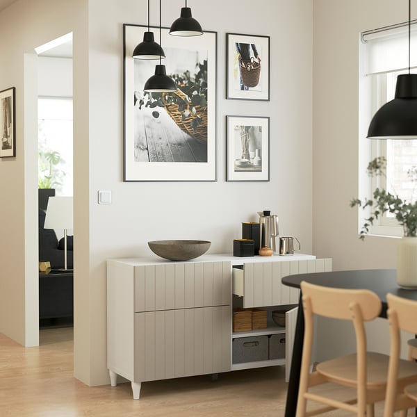 Minimalistlik puhvetkapp riiulite ja sahtlitega, dekoratiivne kauss, fotod ja rippvalgustid avatud eluruumis.