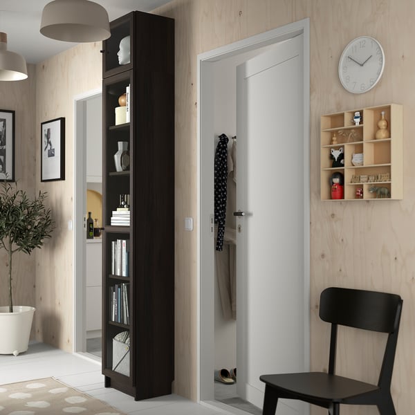 Esik musta BILLY raamaturiiuli, klaasuste, tooli ja seinakellaga.