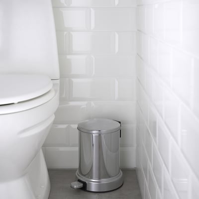 Hõbedane prügikast vannitoas valge suletava kaanega WC-poti kõrval.