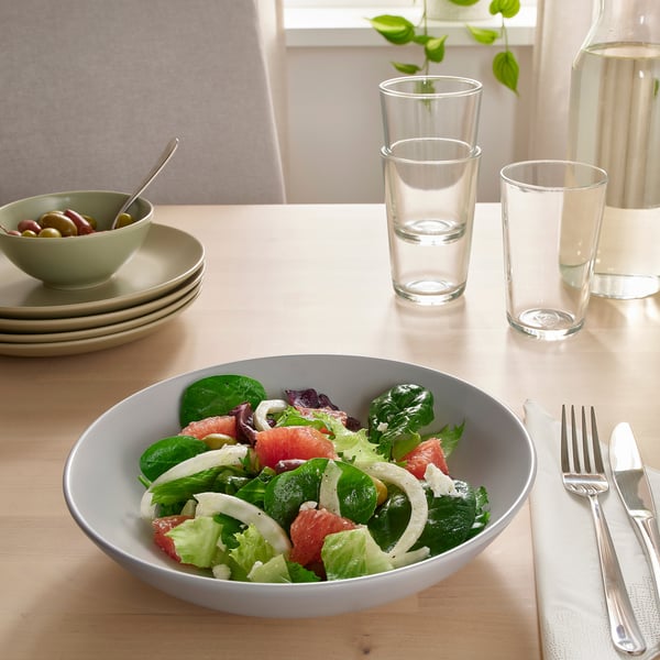 Lauakomplekt FÄRGKLAR roogadega, mis sisaldab salatit. Kaks klaasi, riistad, kauss oliividega on samuti nähtavad.