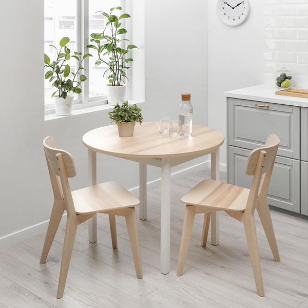 Minimalistlik söögikoht puidust laua ja toolidega, mis sobib ideaalselt kompaktsetesse ruumidesse, kaunistatud taimega.