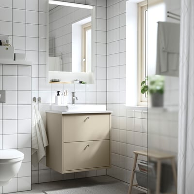 Kaasaegne beež vannitoa, seinale kinnitatud sahtlitega, ristkülikukujulise kraanikausi ja peegeliga. Puhas, minimalistlik disain.