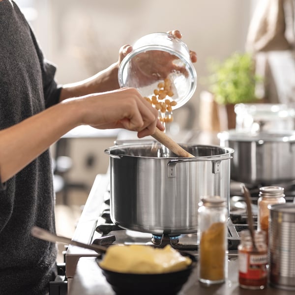 Inimene valab pasta pliidil kurnakaanega suurtesse pottidesse. Läheduses on erinevad vürtsid ja kauss.