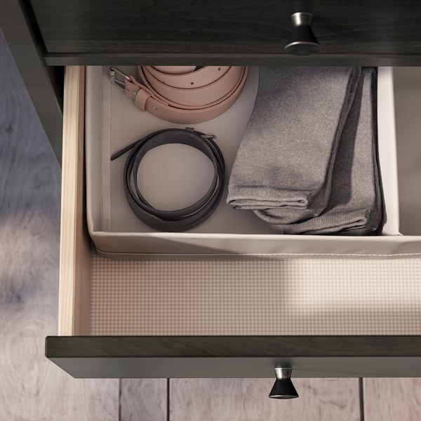 Avatud sahtel, millel on vööd, kenasti volditud riided klanitud moodsas kummutis.