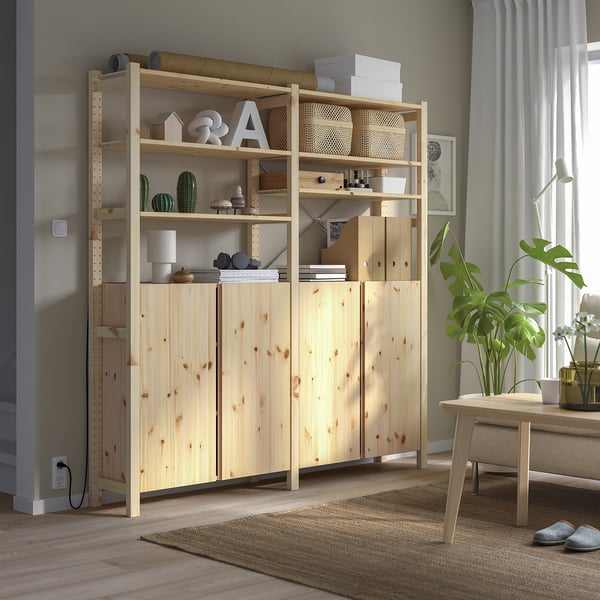 Heledast puidust IVAR riiulite ja kappidega panipaik, mis paneb minimalistlikus toas välja sisekujunduse ja raamatud.