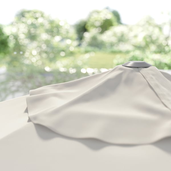 Lähivõte helebeežidest JOGGESÖ päikesevarjudest, ümardatud ülaosa, suletud; seatud roheliste puude vastu.