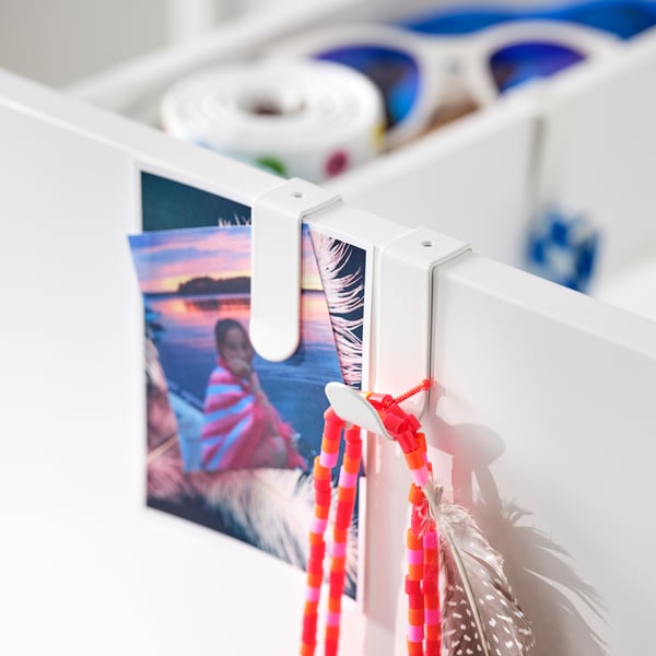 Valge metallist konks, punased helmed, pilt, suled. Dekoratiivne magamistoa sisekujundus.