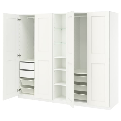 Sellel pildil on avatud sahtlite ja riiulitega valge IKEA PAX riidekapp. See on minimalistlik disain riiete ja aksessuaaride korraldamiseks.