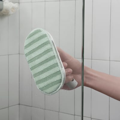 Käes hoides rohelist kobarat PEPPRIG padi, puhastades klaasi, tagades kriimustuskindla pinnahoolduse.