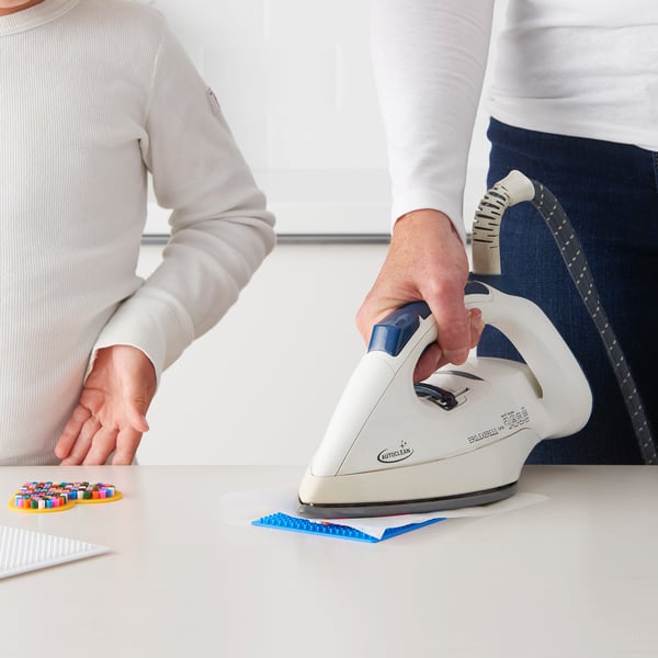 Inimene triikib laual värvilisi helmeid.