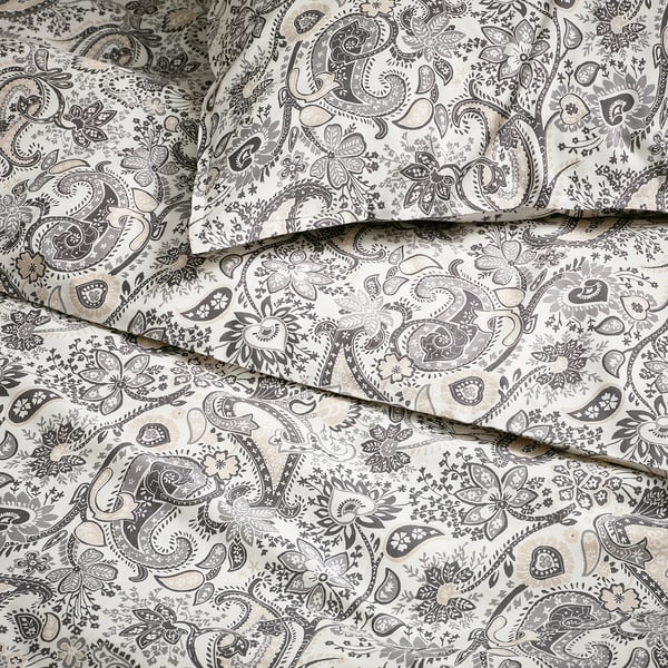 Elegantne paisley-mustriga voodipesu, millel on keerukad lillemustrid helebeežil kangal, mis on kenasti väljapanekuks paigutatud.