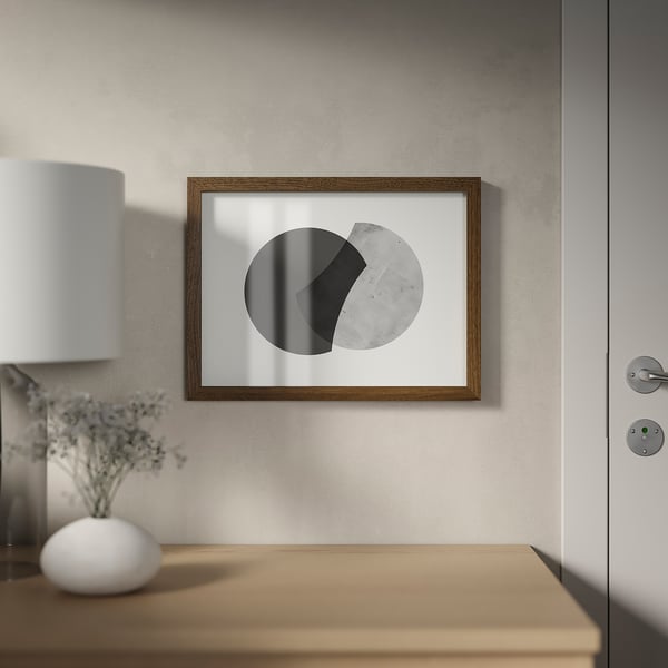 Raamitud minimalistlik kunstiteos ripub ukse kõrval seinal. Alloleval laual on lamp ja vaas lilledega, luues hubase keskkonna.