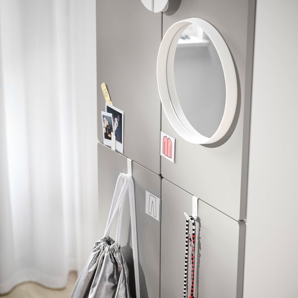 Moodne hall SMÅSTAD riidekapp ümmarguse peegli ja konksudega. Sellel on mitu sektsiooni ja hoidikut, mis kuvavad selliseid esemeid nagu pildid ja kotid.