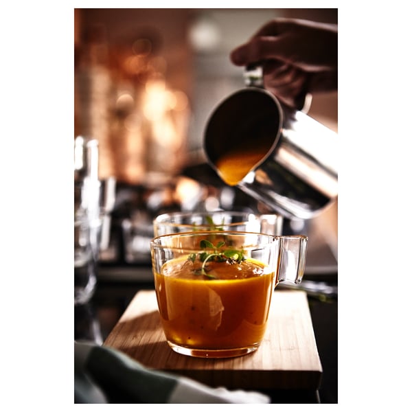 Barista valab apelsinijoogi läbipaistvasse klaaskruusi puidust tööpinnale.