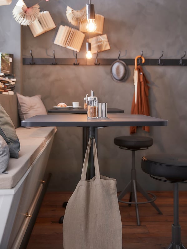 Kaasaegne ruudukujuline söögilaud elegantse musta metallist aluse ja halli lauaplaadiga. Kaks konksu all. Ideaalne väikestesse ruumidesse.