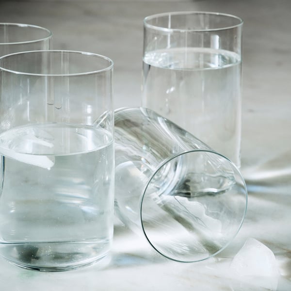 Kolm klanitud, suuspuhutud sirgete servadega klaastopsi, millest igaüks on osaliselt täidetud selge vedelikuga, paigutatud kenasti siledale pinnale.