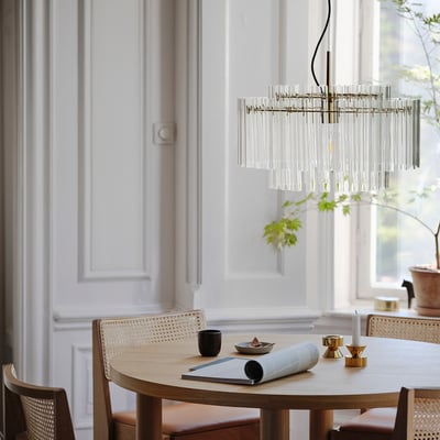 Kaasaegne söögituba STOCKHOLM 2025 lühtriga puidust laua kohal, vitstest toolid ja sisekujundus.